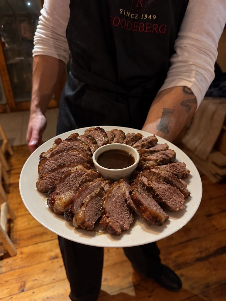 Sliced rump cap arranged around a bowl of sauce