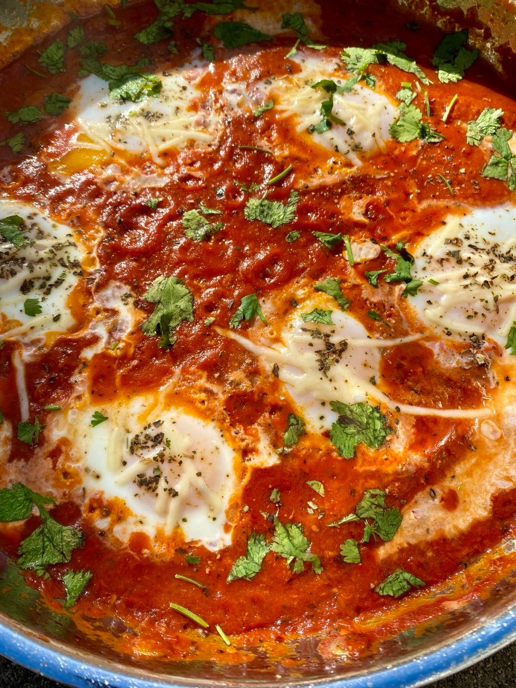 Shakshuka with baked eggs, cheese and coriander in a pan